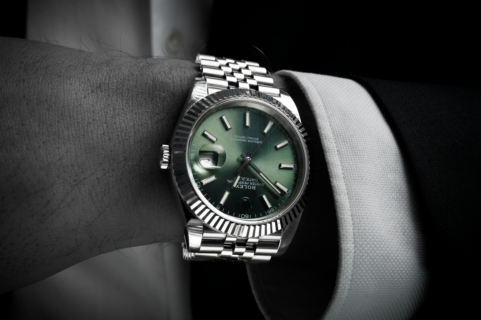 Steel Rolex Datejust 41 with green dial, fluted bezel and jubilee bracelet, on the wrist with a suit cuff