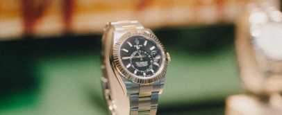 Rolex Sky-Dweller with black dial and fluted bezel on an Oyster bracelet, on a display stand