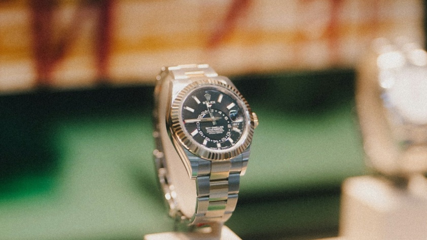 Rolex Sky-Dweller with black dial and fluted bezel on an Oyster bracelet, on a display stand
