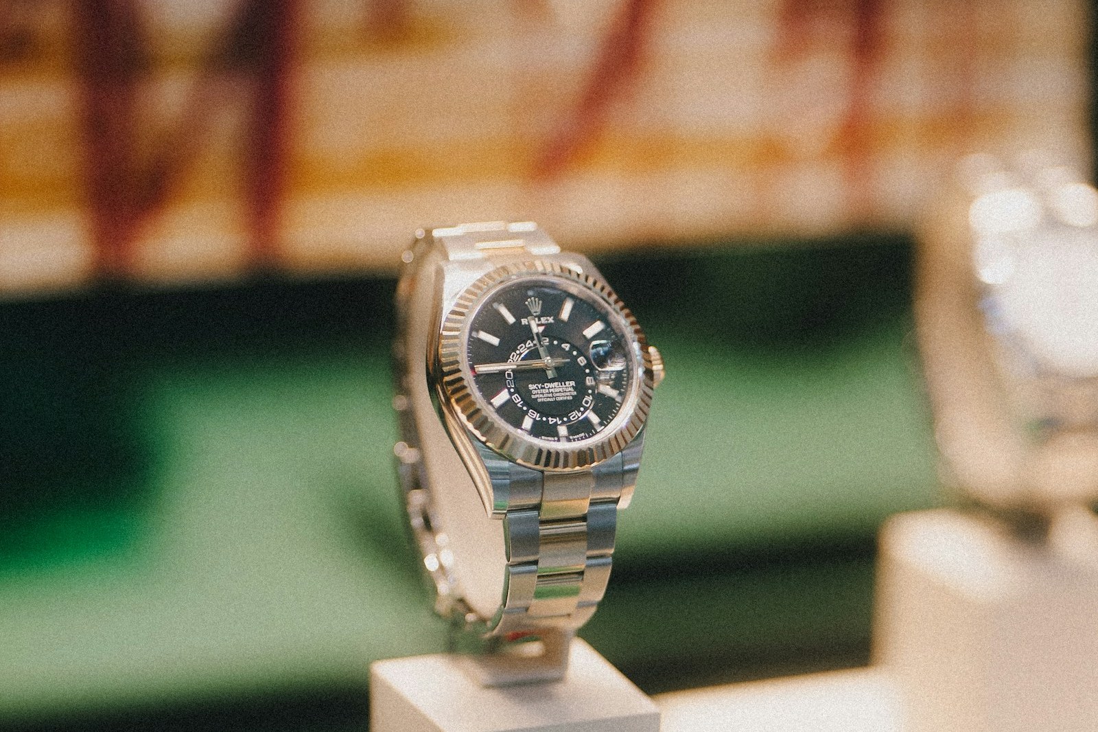 Rolex Sky-Dweller with black dial and fluted bezel on an Oyster bracelet, on a display stand